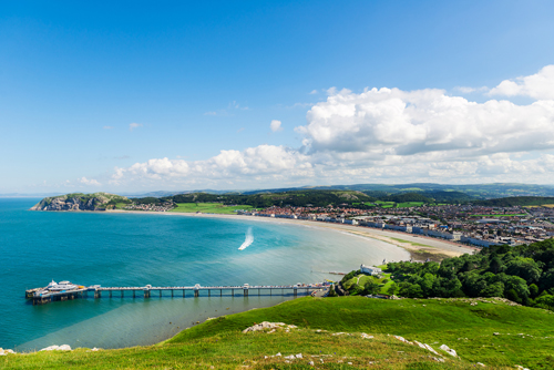 Sunny day at Llandudno seafront, Wales, showing the sea and pier from a green field