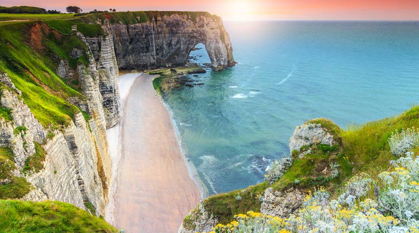 Normandy cliffs and sandy beach under a pink sky